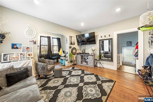 living area with wood finished floors, arched walkways, and recessed lighting