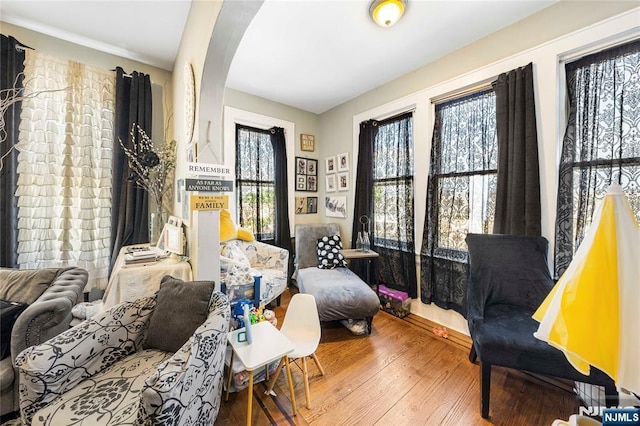 sitting room with hardwood / wood-style flooring and arched walkways