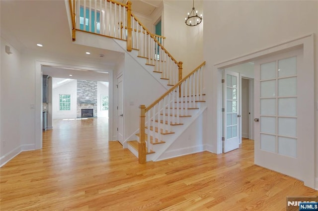 staircase with wood finished floors, a towering ceiling, a chandelier, baseboards, and french doors
