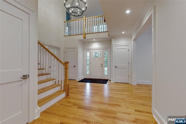 foyer entrance with wood finished floors, stairway, a chandelier, baseboards, and recessed lighting