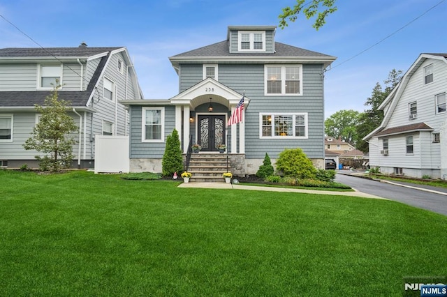 view of front facade featuring a front lawn and a shingled roof