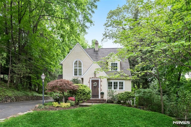 view of front facade with a chimney, a front lawn, and stucco siding