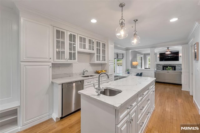 kitchen featuring a sink, stainless steel dishwasher, white cabinets, an island with sink, and crown molding