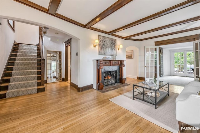 living room with arched walkways, beam ceiling, stairway, hardwood / wood-style floors, and baseboards