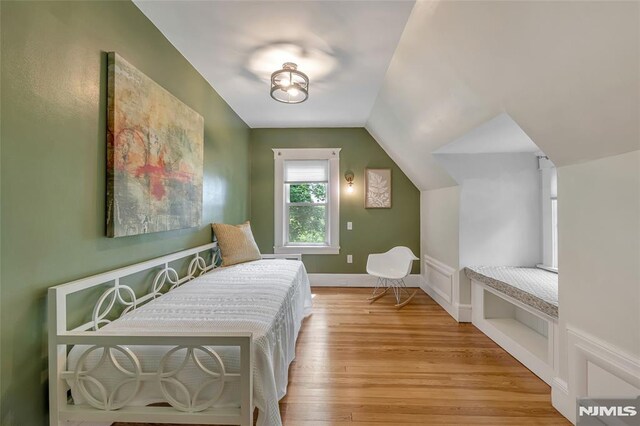 bedroom featuring light wood-type flooring, vaulted ceiling, and baseboards