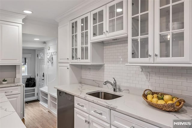 kitchen featuring a sink, stainless steel dishwasher, white cabinets, crown molding, and tasteful backsplash