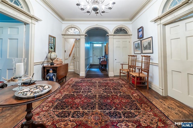 entrance foyer with a chandelier, crown molding, wood finished floors, and baseboards