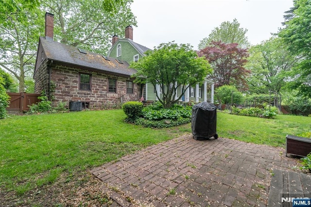 back of house with a patio, a chimney, central AC unit, and stone siding