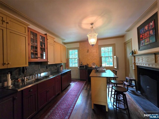 kitchen with a sink, a kitchen island, dark wood finished floors, a kitchen breakfast bar, and glass insert cabinets