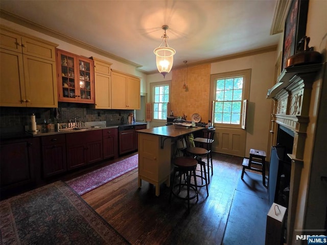 kitchen with a sink, a kitchen bar, dark wood-style floors, glass insert cabinets, and backsplash