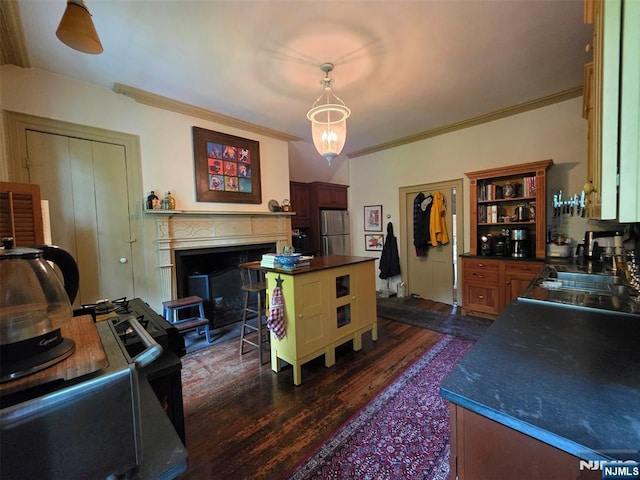 kitchen with freestanding refrigerator, dark countertops, dark wood-style floors, a sink, and crown molding