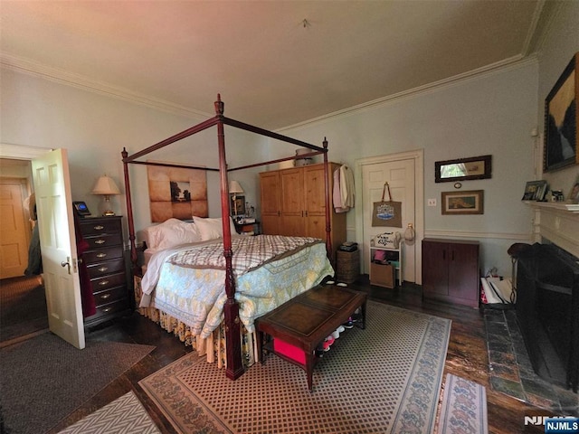 bedroom with wood finished floors, crown molding, and a fireplace