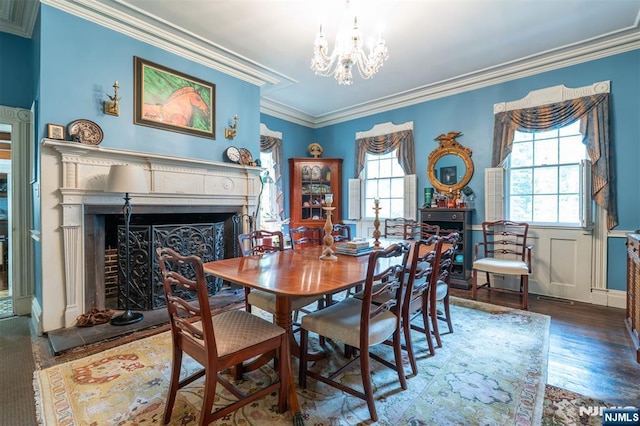 dining room with a chandelier, ornamental molding, a fireplace, and wood finished floors