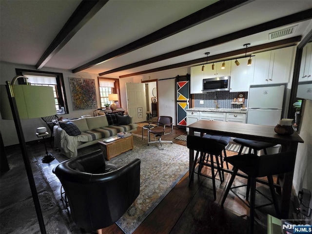 living room with a barn door, beam ceiling, and dark wood-style flooring