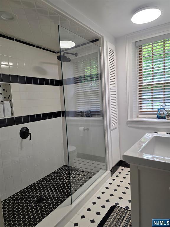 bathroom with a tile shower, tile patterned floors, and vanity