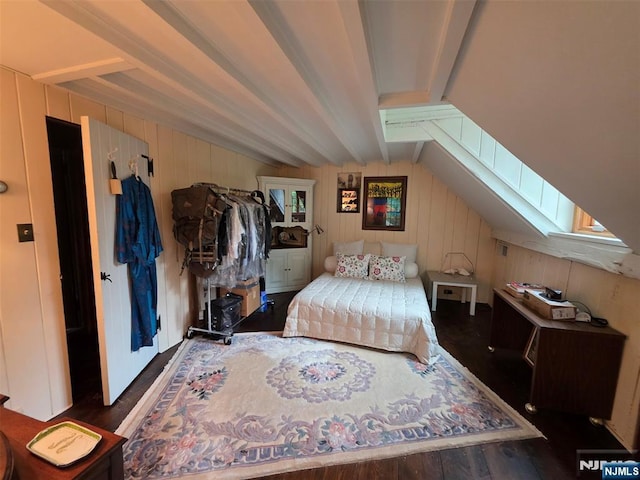 bedroom featuring a skylight, beam ceiling, wood finished floors, and wood walls