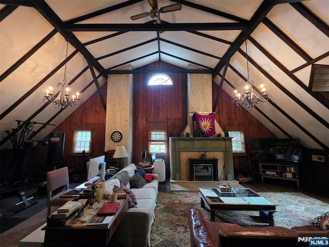 living room featuring a chandelier, vaulted ceiling, wood walls, ceiling fan, and a glass covered fireplace