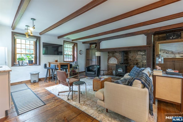 living room featuring a wood stove, hardwood / wood-style floors, and beam ceiling