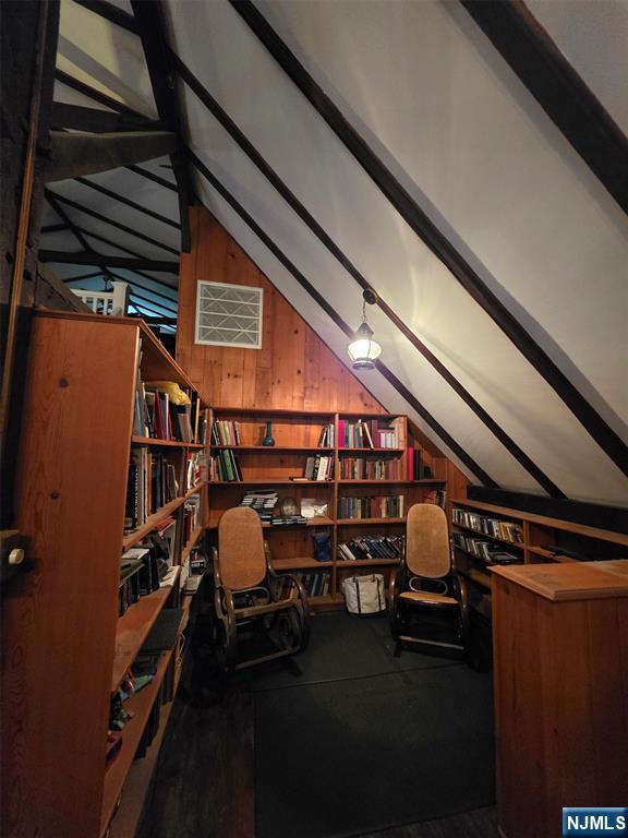 office space with lofted ceiling and wooden walls