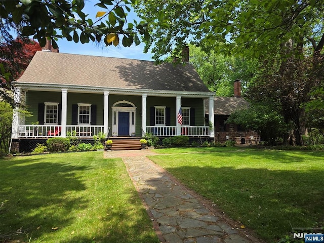 view of front of house featuring a chimney, a porch, and a front yard