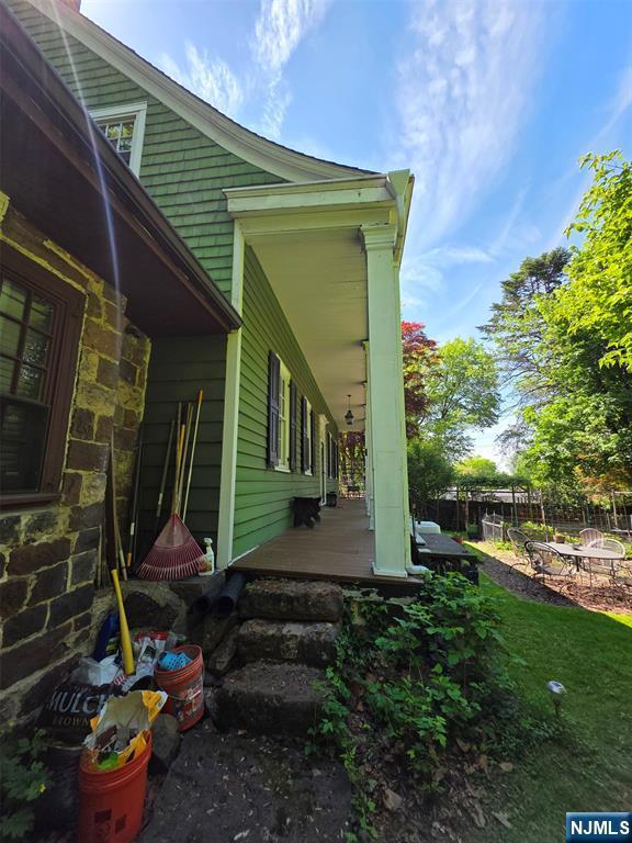 view of side of home with stone siding and covered porch