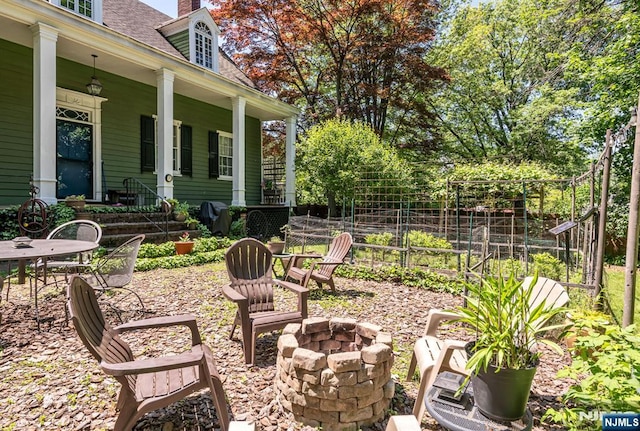 view of yard featuring a fire pit, covered porch, and outdoor dining area