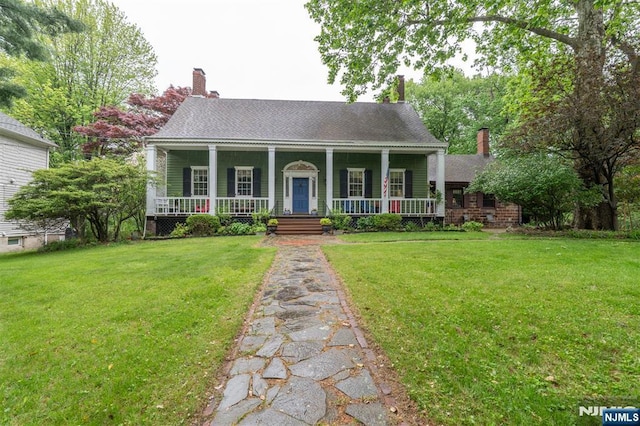 view of front of home with a chimney, covered porch, and a front lawn