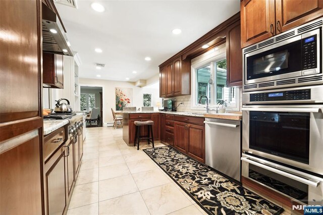 kitchen featuring stainless steel appliances, a peninsula, tasteful backsplash, a warming drawer, and recessed lighting