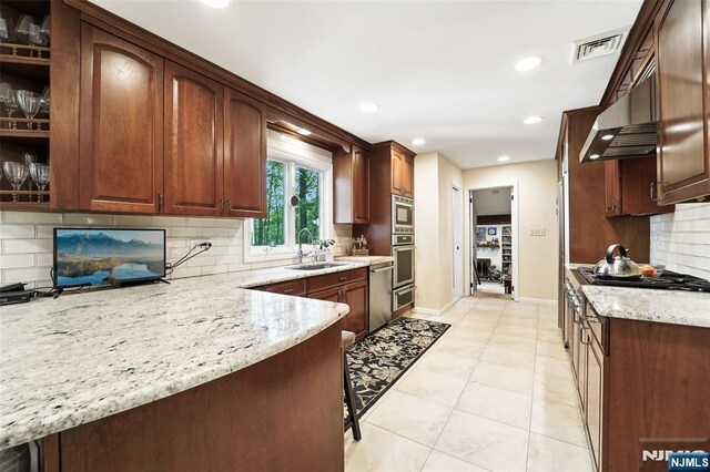 kitchen featuring stainless steel appliances, a sink, light stone countertops, decorative backsplash, and recessed lighting