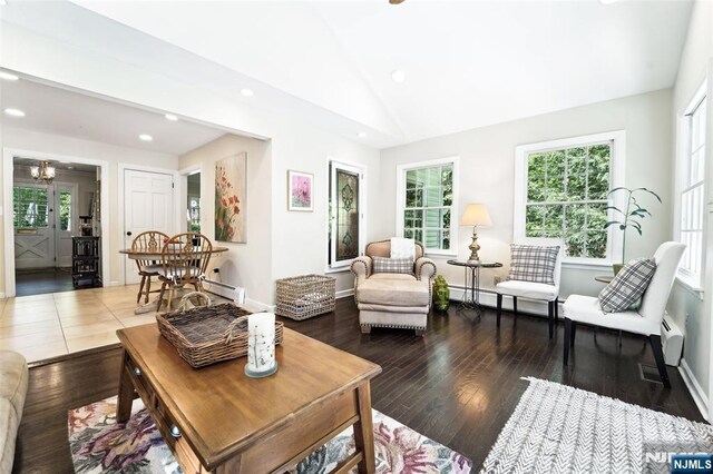 living area featuring hardwood / wood-style flooring, vaulted ceiling, recessed lighting, baseboard heating, and baseboards