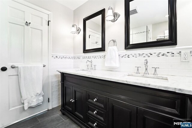 full bathroom with double vanity, tile patterned flooring, tile walls, and a wainscoted wall