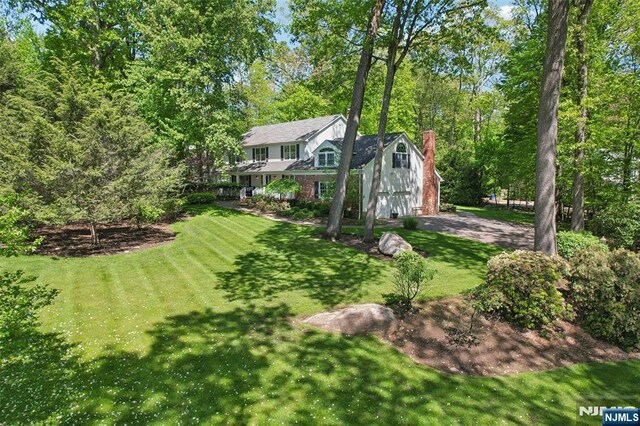 view of green lawn featuring a garage and driveway
