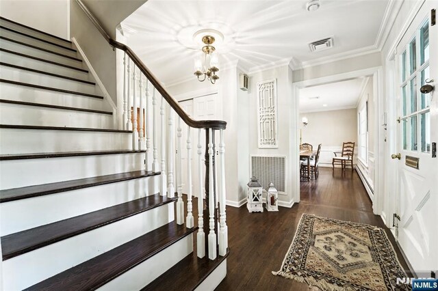entryway featuring stairs, a chandelier, ornamental molding, wood finished floors, and baseboard heating