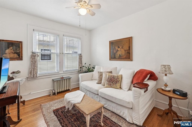 living room with radiator, wood finished floors, a ceiling fan, and baseboards