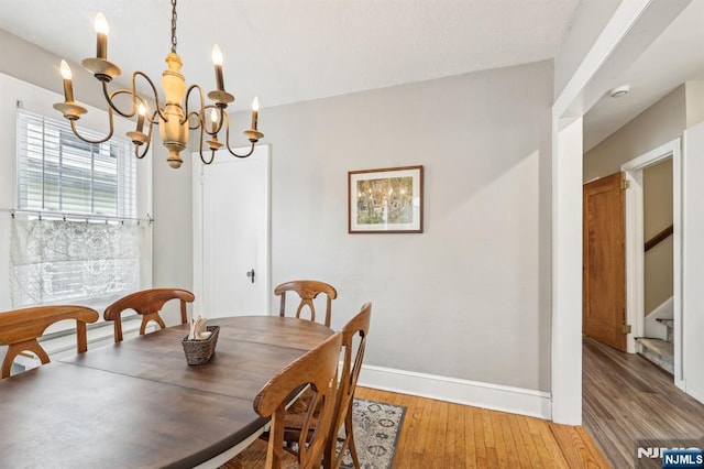 dining area with light wood finished floors, a chandelier, baseboards, and stairs