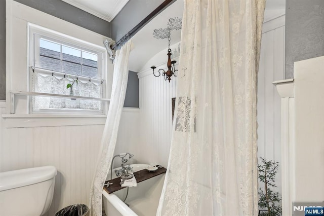 full bathroom with toilet, a bathtub, a wainscoted wall, and ornamental molding