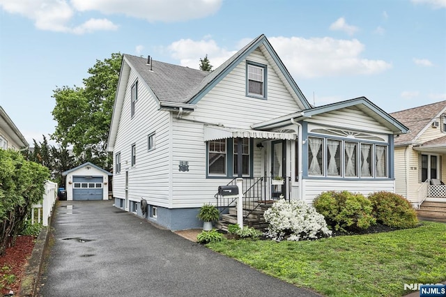 bungalow-style house with an outdoor structure, a detached garage, and driveway