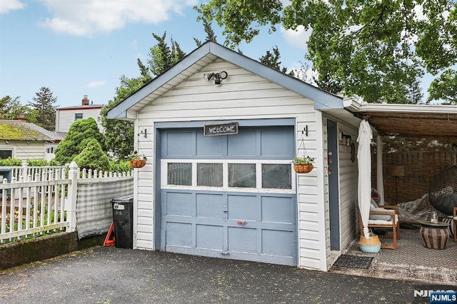 detached garage featuring fence and asphalt driveway
