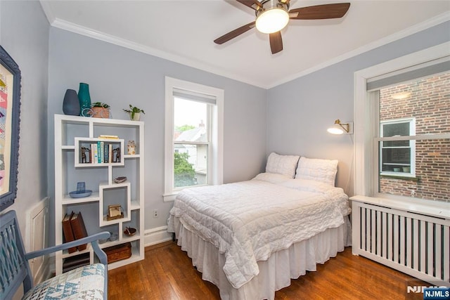 bedroom with radiator, wood finished floors, crown molding, a ceiling fan, and baseboards