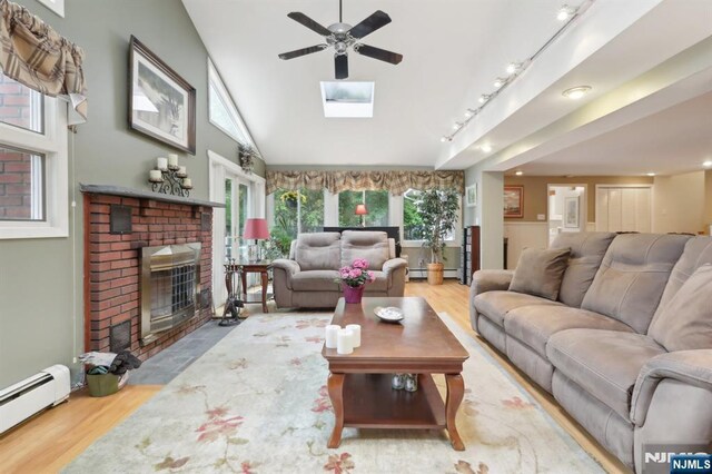 living area with a baseboard heating unit, wood finished floors, ceiling fan, a fireplace, and lofted ceiling