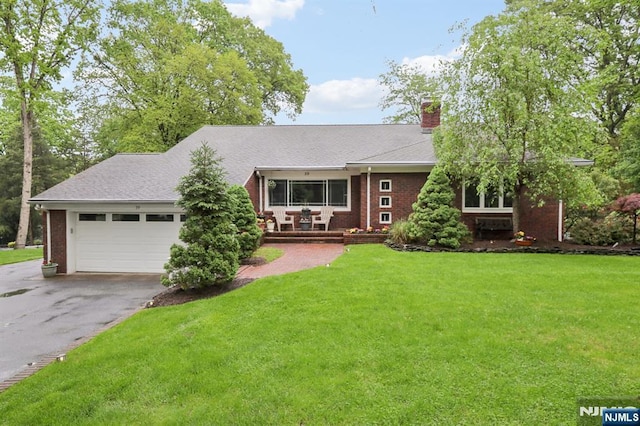 view of front facade featuring driveway, an attached garage, a front lawn, and brick siding