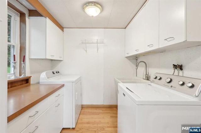 washroom featuring washing machine and clothes dryer, cabinet space, light wood-type flooring, and plenty of natural light