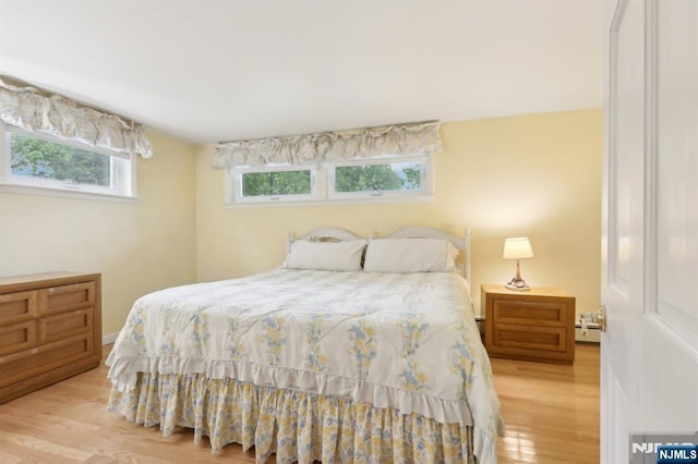 bedroom featuring wood finished floors and a baseboard radiator