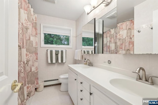 bathroom with a baseboard radiator, tile walls, toilet, double vanity, and tasteful backsplash