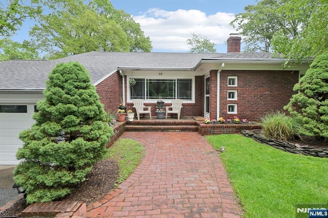 ranch-style home with a chimney, brick siding, a front lawn, and a garage
