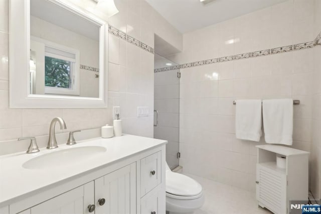 full bath featuring tile walls, vanity, toilet, tiled shower, and decorative backsplash