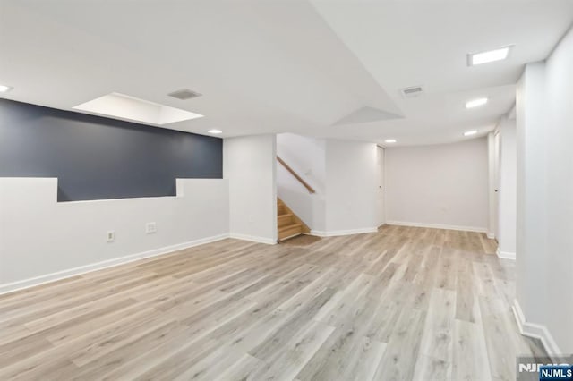 finished below grade area featuring light wood-style flooring, stairway, baseboards, and recessed lighting
