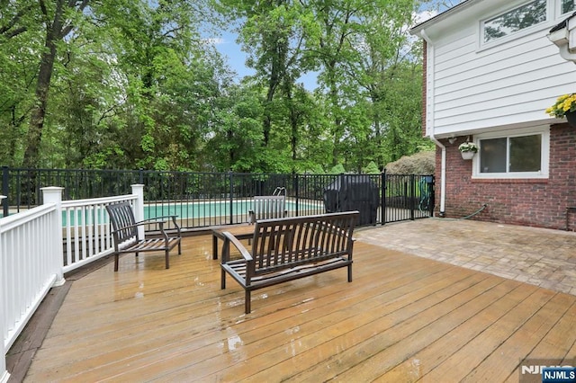 wooden deck with view of wooded area and fence