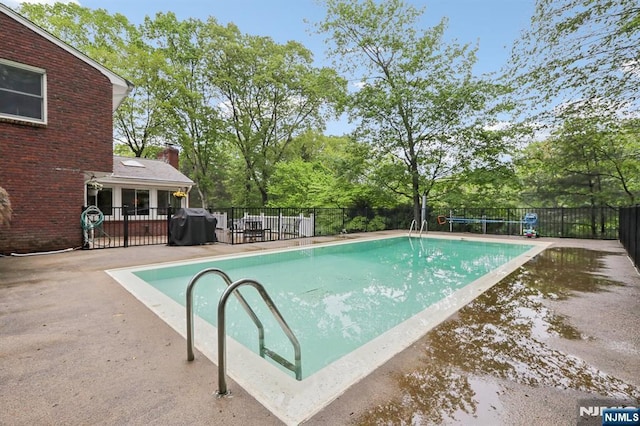 view of swimming pool with fence, view of scattered trees, and a patio area