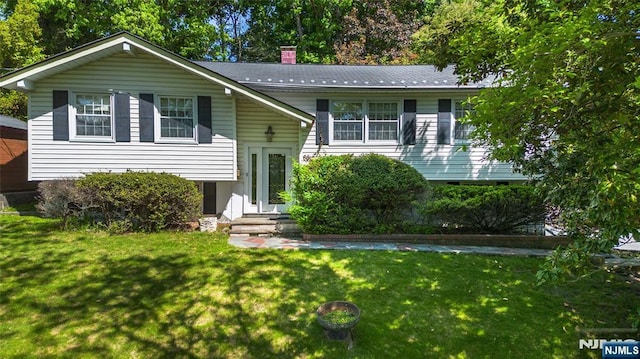 raised ranch featuring a front lawn and a chimney